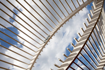 White Wooden Arbor/Pergola with blue sky in distance.