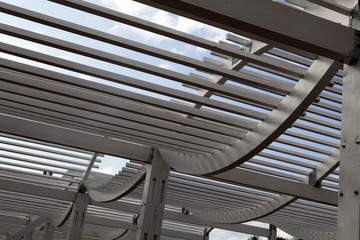 White Wooden Arbor/Pergola with blue sky in distance.