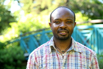 Young african man, smiling, outdoor in park, looking into the camera