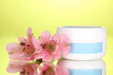 Obraz na płótnie Canvas Jar of cream with flower on green background