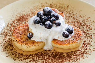 curd with cream and currants on a yellow plate