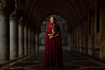 Naklejka premium Woman with a mask wearing red cloak outdoor