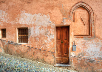 Wooden door and small paved street in Saluzzo.