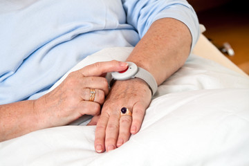 Seniorin mit Ruf Hile Notfall Telefon im Bett