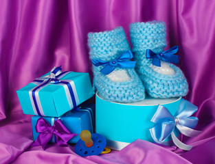 blue baby boots, pacifier, gifts on silk background.