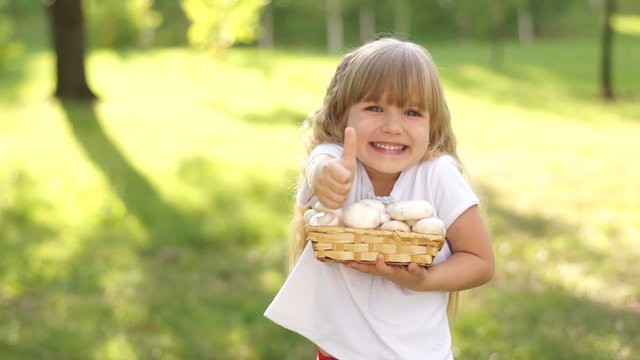 Child with a basket of mushrooms. Thumbs up. Ok