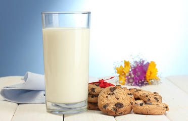 glass of milk, chocolate chips cookies with red ribbon and