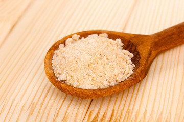 Brown sugar in spoon on wooden background