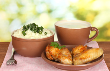 Mashed potato in the bowl and roasted chicken wings in the