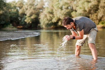 man splashing water on his face into the river - series
