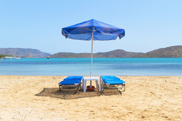 Blue deckchairs under parasol at Aegean Sea