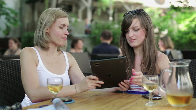 Female friends with tablet computer in cafe