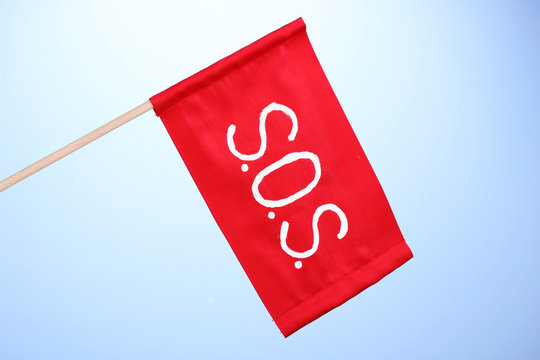 SOS signal written on red cloth on blue background