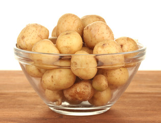 young potatoes in a glass bowl on a table on white background