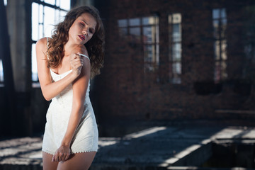 Fototapeta premium Young brunette posing against the backdrop of a building with l
