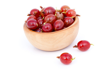 fresh red gooseberries in a wooden bowl, over a white background