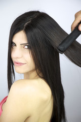 Beautiful female model getting long hair straightened with iron