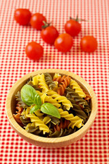 Multicolored pasta uncooked with a leaf of basil