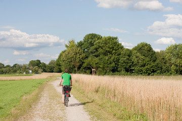 Obraz premium Junger Mann fährt Fahrrad auf Feldweg