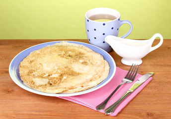 Stack of tasty pancakes on wooden table on green background