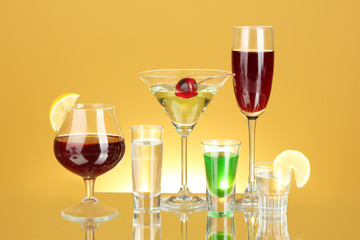 a variety of alcoholic drinks on yellow background