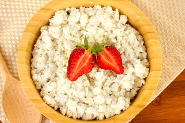 cottage cheese with strawberry in wooden bowl with wooden spoon