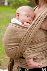 Newborn baby sleeping in a sling, in the embrace of her mother - obrazy, fototapety, plakaty