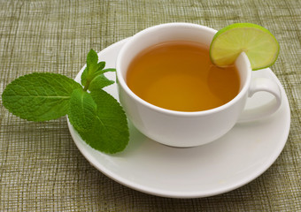 White cup with a branch of mint and limes