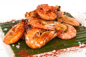 fried black tiger prawns with herbs and spices on banana leaf