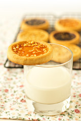 Cookie on a glass of milk with more cookies in background