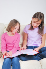 Two sisters student on the couch with a notebook