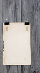 black clip and old blank note paper hang on wood panel