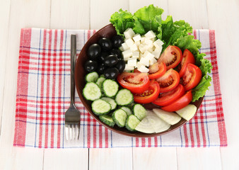 tasty Greek salad on white wooden background