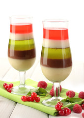 fruit jelly in glasses, berries and mint on wooden table