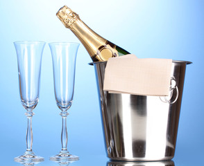 Champagne bottle in bucket with ice and glasses