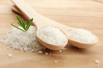 salt in spoons with fresh  rosemary on wooden background