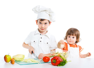 Two smiling kids mixing salad