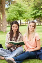 Portrait of female teenagers sitting with a textbook