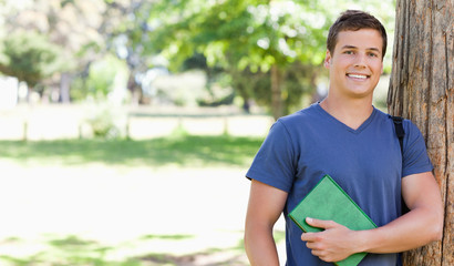 Portrait of a smiling muscled student holding a textbook