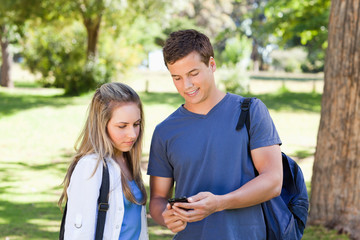 Fototapeta premium Close-up of a student showing his smartphone to a girl