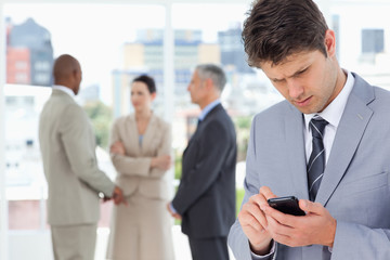 Young serious manager using his cell phone to send a text