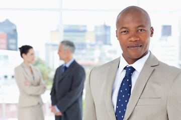 Young executive in a suit standing upright while his team is beh