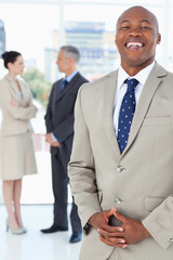 Young businessman laughing while standing upright with his hands