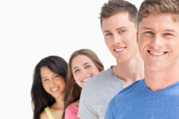 Four smiling people standing in front of one another at a slight