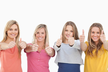 Four smiling girls giving the thumbs up