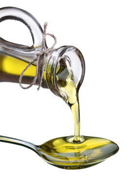 Olive oil is poured from a bottle into a spoon.