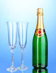 Bottle of champagne and goblets on blue background