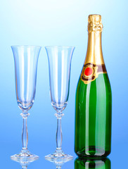 Bottle of champagne and goblets on blue background