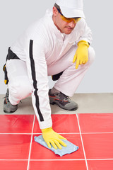 worker with yellow gloves blue towel clean red tiles grout