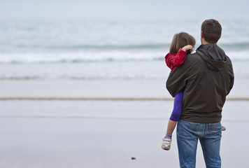 Padre con hija en cuello mirando al mar